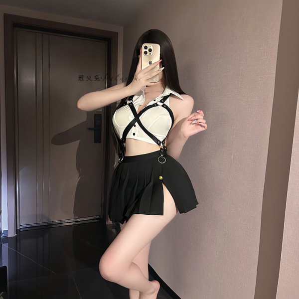 Woman modeling a white and black sailor-themed lingerie set with suspenders and pleated skirt, taking a mirror selfie in a st...