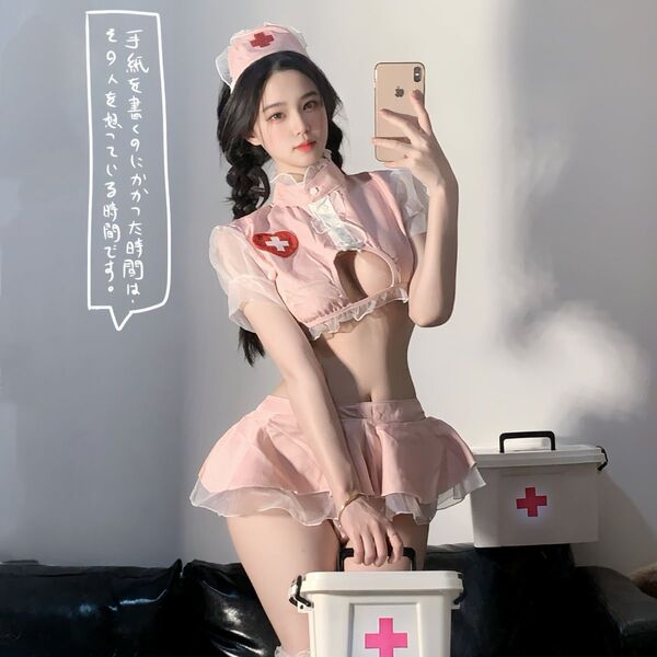 Woman in pink sexy nurse costume with heart details, posing with medical props for cute role play outfit.
