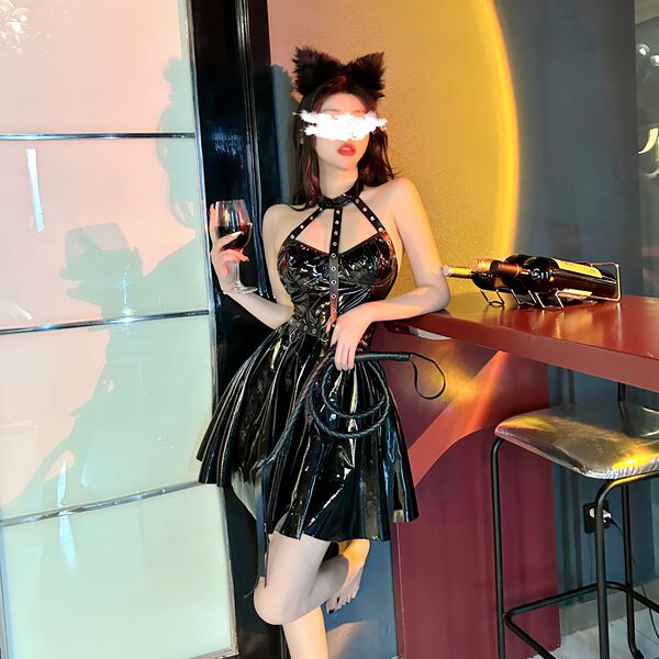 Woman in shiny black pvc catwoman costume with lace-up bodysuit, garter belt, and thong, holding wine glass and whip.