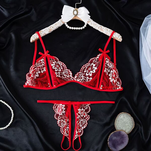Red lace lingerie set with floral embroidery, displayed on a hanger with pearls and decorative stones.