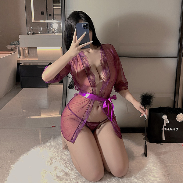 Woman wearing sheer mesh lace sleepwear set with purple ribbon, posing in bedroom.