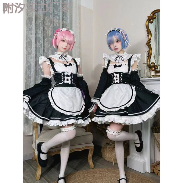 Two women dressed as maid characters from re:zero, wearing black and white outfits with ruffles and bows, posing indoors.