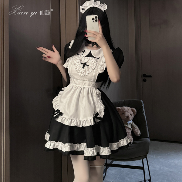 A woman poses in a black and white maid costume with ruffles, holding a phone. the outfit features a collar and apron design,...
