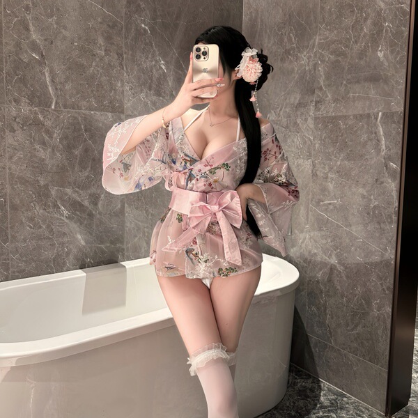 Woman in pink floral yaseyese kimono-style lingerie set with bow, sheer sleeves, and thigh-highs, posing in bathroom mirror.