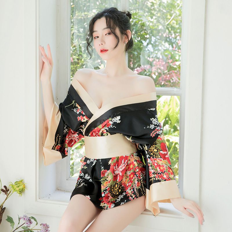 A woman poses by a window wearing a black floral hua ying japanese kimono-style lingerie set, featuring off-the-shoulder desi...