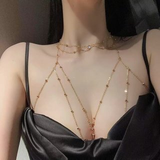 Woman wearing a gold cherry blossom body chain with crystals over a black top.