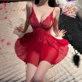 Woman wearing red lace mesh sleep dress with strappy design, sheer provocative lingerie nightgown on bed with rose petals.