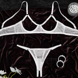 Sheer white bra and panty set with pink polka dots on dark velvet, styled with pearls and flowers.