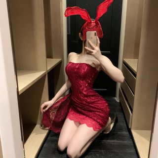 A woman poses in a mirror wearing a red lace dress with bunny ears, capturing a playful and elegant moment. the dress feature...
