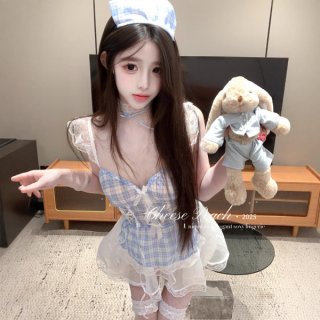 Woman wearing a blue plaid maid outfit with sheer lace sleeves and deep v top, holding a stuffed bunny.