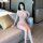 Woman wearing plus size deep v-neck sheer mesh lace nightgown, seated on sofa in hotel room.
