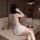 Woman wearing white lace sheer bodycon nightdress set, embroidered mesh babydoll lounge sleepwear, sitting on sofa.
