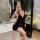 Woman wearing black lace-trimmed slip dress in bedroom, showcasing plus size sexy sleepwear with deep v-neck and sheer fabric...