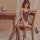 Woman wearing qingyege deep-v lace bodysuit with sheer mesh and open-crotch design, seated on wooden chair in bedroom.