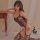 Woman wearing qingyege sexy deep-v lace bodysuit with sheer mesh and open-crotch design, posing seductively on bed.