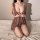 Woman kneeling on bed in sheer lace lingerie set, deep v-neck with ruffle straps, sensual nightwear for women.