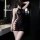 Woman wearing black lace halter neck bodysuit with sheer mesh panels and cutout sides, styled as a seductive bodycon sleep dr...