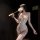 Woman in white lace bodysuit with sheer panels, removable cups, and matching thigh-high stockings holding a feather wand.