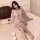 Woman wearing sheer pink princess sleep dress with lace backless design, chest and hip reveal, on bed with candles.