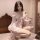 Woman wearing sheer princess sleep dress with lace backless design, chest and hip reveal, in soft bedroom setting.