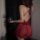 Woman in red lace bodysuit with sheer mesh, low-cut bust, and cut-outs, holding wine glass.