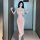 A woman poses confidently wearing a form-fitting, blush-colored lace sleepwear set. the dress features a deep v-neckline and ...