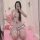 Woman in white and red maid costume with bows, posing on pink carpet with plush toy, ideal for role play.
