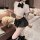 Woman modeling plus size jk uniform set with white crop top, black bow, and pleated mini skirt in bedroom setting.