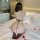 Woman in plus size sexy lace bodysuit with open-crotch design, kneeling on bed with rose petals, showcasing back and curves.