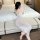 A woman sits on a bed wearing a sheer white backless long-sleeve nightgown dress, ideal for couples vacation loungewear.