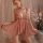 Woman wearing pink lace sleep dress with ruffles and bows, flirty pure-temptation lingerie nightgown from 2025 collection.