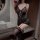 Woman wearing black lace sleepwear set with deep v-neck bodysuit and elastic strap nightgown, holding a red rose.