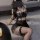 Woman wearing black lace lingerie set with push-up bra, sheer skirt, and fishnet stockings.