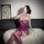 Woman in purple plus size lace bodysuit with underwire and open-crotch design, posing on white fur rug.