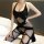 Woman wearing cherry romance sheer open-crotch bodysuit with black fishnet stockings, posing on bed.