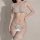 Woman wearing a delicate white lace lingerie set with sheer bralette, matching thong, and garter stockings.