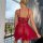 Woman wearing red lace lingerie set, backless sheer bodysuit sleepwear on balcony with city view.