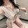 Woman wearing white pure & playful bunny girl costume set with pom-pom ties, sheer top and matching bottoms for cosplay.