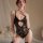 Woman modeling yue die black lace bodysuit with sheer panels and open-crotch design, elegant sleepwear for seductive allure.