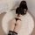 Woman wearing black sheer mesh bodysuit with hip-hugging design, paired with striped thigh-high socks on a fluffy rug.