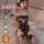 Woman modeling black lace qqny pure allure sleepwear set with sheer bodysuit and fishnet stockings on bed.