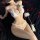 Woman wearing white lace three-piece pearl lingerie set with open-crotch design, feather wand, and rose petals on black fabri...