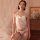 Woman wearing white lace bodysuit set with open-crotch design, pearl necklace, and earrings in soft bedroom setting.