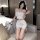 Woman in white sheer lingerie set with lace trim, bow headband, and peace sign gesture on sofa.