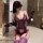 Woman wearing purple lace lingerie set with embroidered sheer bra, panty, gloves, and thigh-highs in bathroom.