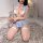 Woman in blue bunny girl lingerie set with white stockings, holding plush rabbit on fluffy rug.