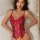 Woman wearing a red sexy lace bodysuit with an open-crotch design, lying on a bed.