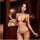 Woman modeling red qingran bikini set with butterfly hip ties and lingerie-style top in warm indoor setting.