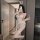Woman in white bunny lingerie set with open-crotch design, holding wine glass, posing for mirror selfie.