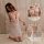 Woman kneeling on bed wearing white lace cami nightgown with sheer mesh, adjustable straps, and open back design.